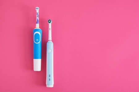 two electric blue toothbrushes on bright pink background oral hygiene concept copy space top viewの写真素材