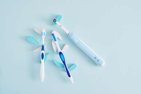 electric and plastic toothbrushes on a blue background, which brushes are more effective in cleaning the oral cavity and more eco-friendlyの写真素材
