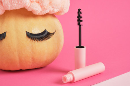 mascara in mock up blank pink packaging and pumpkin with false eyelashes on pink background copy space, make up conceptの写真素材