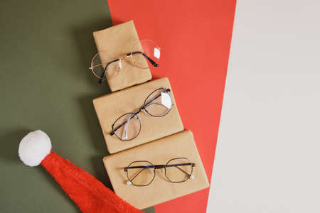 multiple eyeglasses and santa hat on red and green background, optics store sale before christmas, discounts and marketingの写真素材
