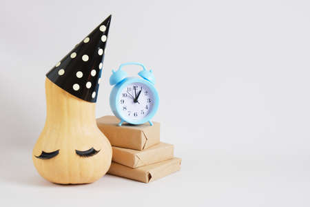 pumpkin in party hat and goft boxes on gray background copy space, new year or christmas minimal...