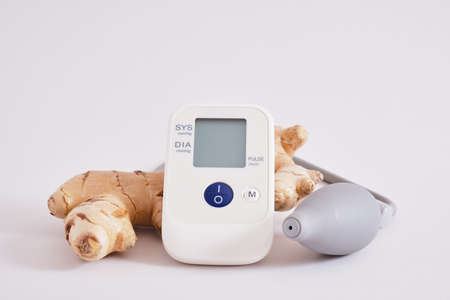 blood pressure monitor and ginger root on gray background, benefits of ibmir for blood pressure...