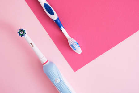 different toothbrushes on pink background, electric toothbrush or plastic toothbrush, environmental friendliness lifestyle concept, efficiency of brushing teethの写真素材