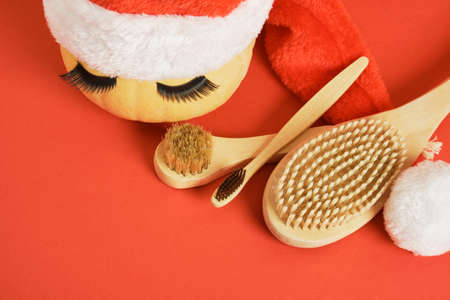 bamboo toothbrush, wooden massage brushes, pumpkin with false eyelashes and towel on gray background, peeling with dry brush massageの写真素材