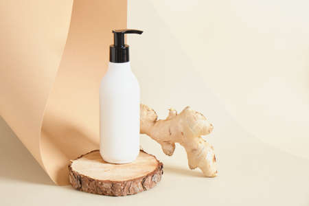 lemon, mock up cream bottle with dispense on wooden stand and ginger root on beige background copy space natural cosmetic conceptの写真素材
