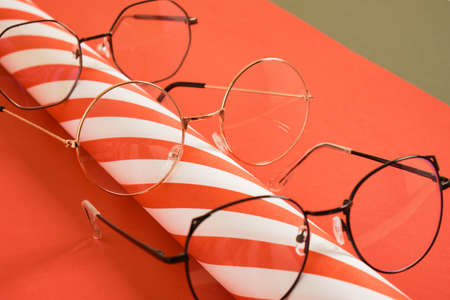 several different stylish eye glasses and a roll of striped wrapping paper, christmas sale in optics store, trendy eyeglass frames, festive atmosphereの写真素材
