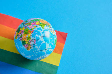 toy ball in the form of a planet and the flag of the lgbtq community, pride concept blue backgroundの写真素材