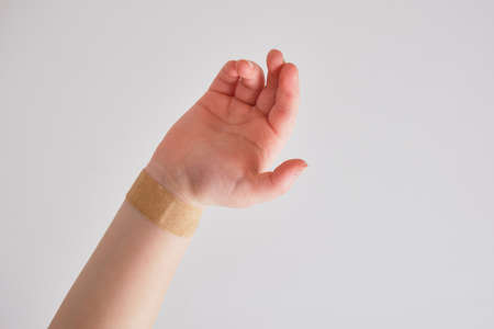 plaster on a child's hand on a gray background, selective focus, copy place, medical plaster on a veinの写真素材