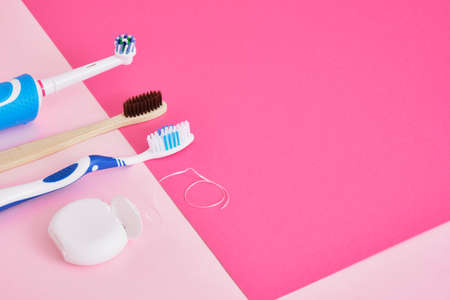 dental floss, electric, bamboo and plastic toothbrushes on a pink background, which brushes are more effective in cleaning the oral cavity and more eco-friendlyの写真素材