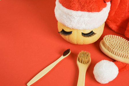 bamboo toothbrush, wooden massage brushes, pumpkin with false eyelashes and towel on gray background, peeling with dry brush massageの写真素材
