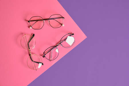 different fashion eye glasses on pink and purple geometric background, trendy eyeglasses frames copy spaceの写真素材
