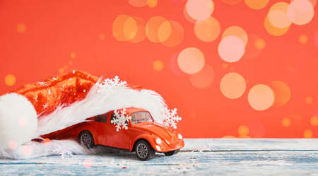 miniature red retro car model in red santa hat, christmas backgroundの写真素材