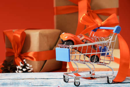 Christmas time shopping, miniature red retro car model in shopping cart and festive decoration