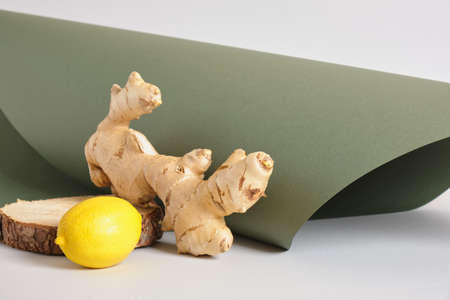 ginger root, lemon and wooden stand on gray and green background, mock up cosmetic background