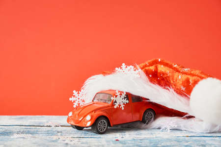 miniature red retro car model in red santa hat, christmas backgroundの写真素材