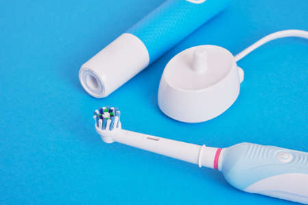 electric blue toothbrushes and charging station for them on a blue background copy space