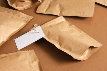 mock up blank paper bags and white cardboard tag on brown background Eco friendly packaging, paper recycling, zero waste, natural products concept. Copy space.の写真素材