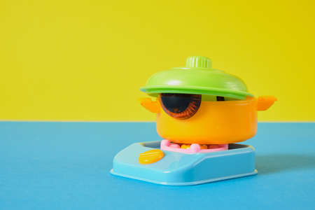 friendly funny face concept, toy eyes in a plastic pot with a lid on the toy cooking stove, original...