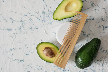 white mock up jar for cosmetics, cut in half avocado and wooden comb on light background