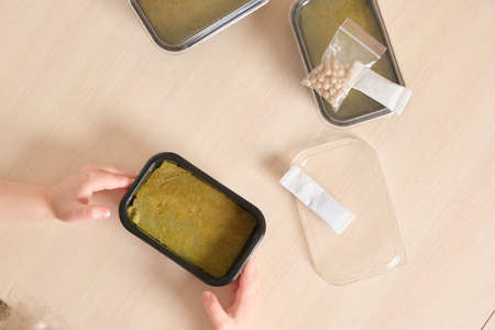 a child and a set for growing microgreens at home, children's hands hold a container with a jute mat