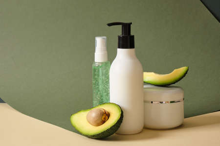 moc up cream jar and two bottles with dispenser and avocado slices on a beige background. natural cosmetics concept.copy spaceの写真素材