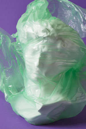 david head in transparent plastic bag on purple background copy space, art decline, environmental pollution slices conceptの写真素材