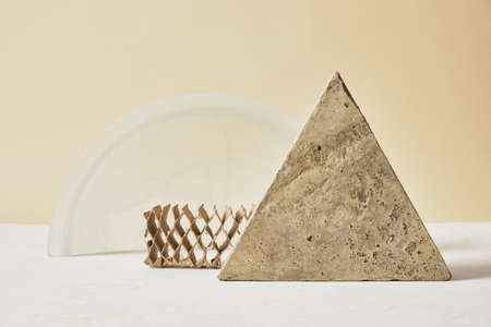 concrete tile in the shape of a triangle, cardboard and a glass arch on a light background, mock-up...