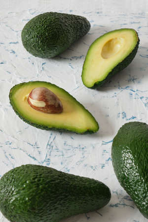 fresh sliced and whole avocado fruit on textured background in a row close up selective focus