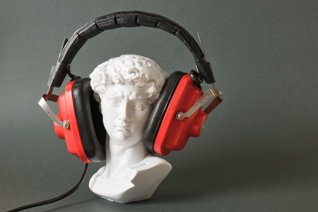 fake bust of david with retro headphones on dark green background copy spaceの写真素材