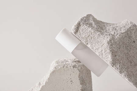 Transparent bottle of perfume on artificial stone stage on a gray background. Women's and men's...