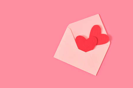 red felt hearts in a bright paper envelope on a pink background valentine postcard concept...