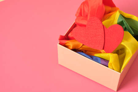 two red felt hearts, rainbow flag symbol of the lgbt community in a box, pink background, valentine's day concept, romance for same-sex couplesの写真素材