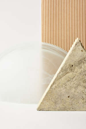 concrete tile in the shape of a triangle, beige corrugated cardboard and a glass arch on a light...
