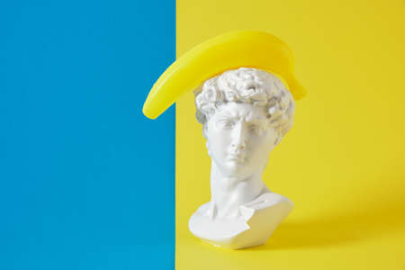 April 1 date. April Fool's Day. creative minimal concept. creative concept for april's day with a replica of the bust of david in a banquet hat and a fake bananaの写真素材