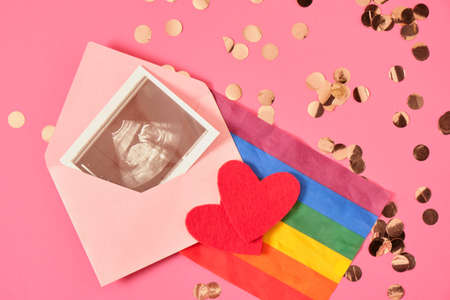 red felt heart and flag rainbow of colors and pregnancy ultrasound scan in pink envelope, pregnancy...