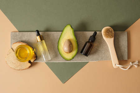 natural cosmetics on sonov avocado, mock-up dropper bottles with pipettes, massage wooden brush and...