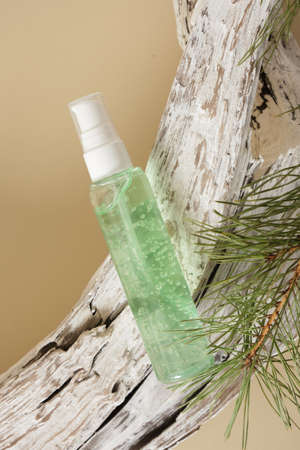 cosmetic green bottle gel and painted log and pine branch on beige background, natural product presentation mock-up backgroundの写真素材