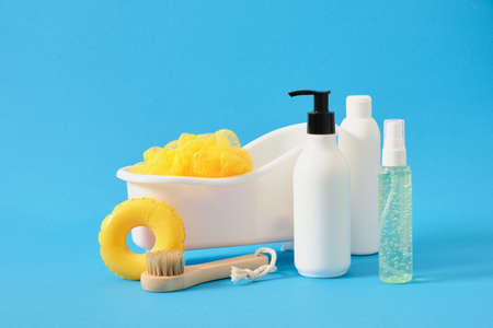 body care products in mockup bottles, washcloth and massage brush in a toy bath, bathing concept