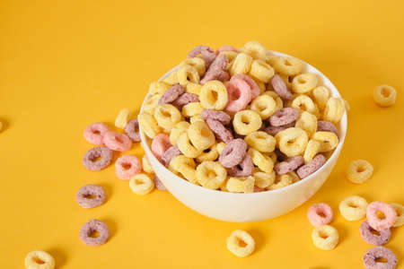 colored breakfast cereals laid out in a bowl on a yellow background top view, childrens healthy breakfast copy spaceの写真素材