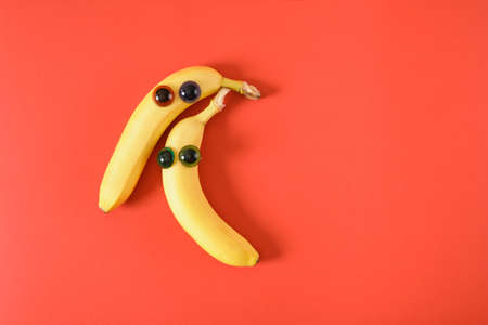 two banana face with eyes, cheerful faces made of plastic doll eyes and fresh yellow bananas red background 14 february conceptの写真素材
