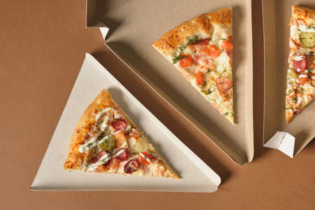 a slices of pizza in a cardboard box in the shape of a triangle for serving and take away, fast food...