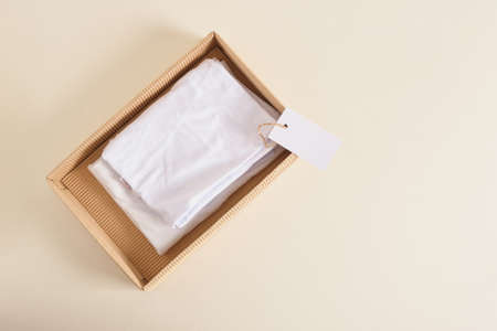 white cotton clothes in craft box and blank white paper label mock up