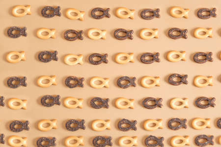 a pattern of cookies in the shape of a fish on a beige background, cookies in chocolate glaze copy space top viewの写真素材