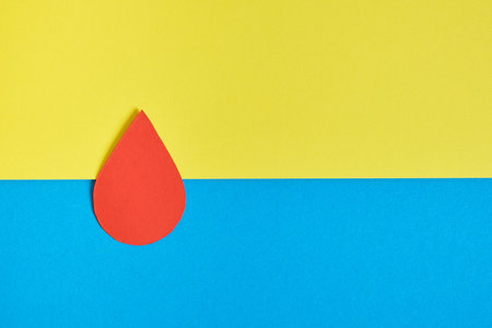 paper blood drop on yellow and blue background copy space war in ukraine conceptの写真素材