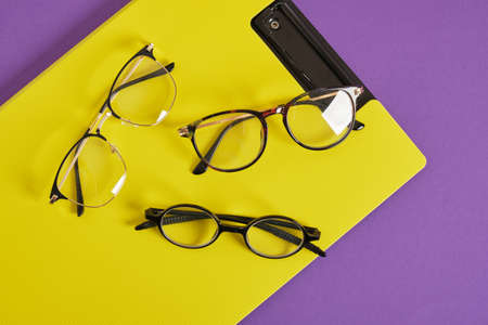 trendy eye glasses on a purple and yellow background glasses for study, computer work and reading, fashionable eyeglass framesの写真素材