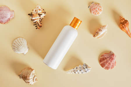 white mockup bottle for cosmetics without a label and sea shells on a beige background, sunscreen, suntan lotion, summer skin careの写真素材