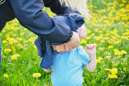 mother trying to put a sweater on a naughty boy, a child with special needs, a summer field child does not want to dressの写真素材