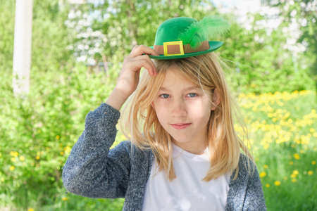 teenage girl in a green leprechaun hat on the background of nature, st patrick's day conceptの写真素材