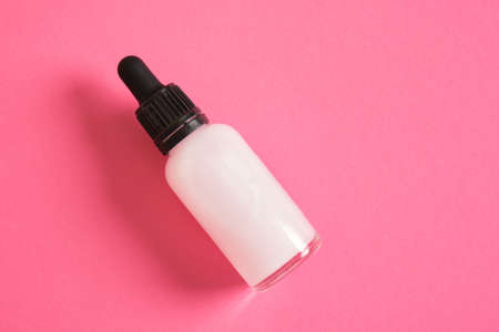 pink cosmetic serum for skin care in a transparent dropper bottle on bright pink background copy space top view mock upの写真素材