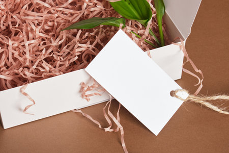 green leaves, and an empty tag in a white mockup box filled with strips of pink paper on a brown...